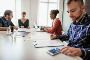 mensen vergaderen met rekenmachine en post-its op tafel