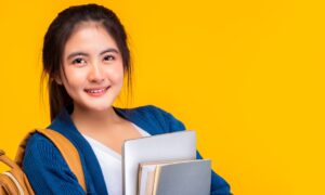 lachend meisje draagt laptop en schoolboeken